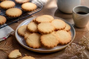 Biscuits sablés de grand-mère dorés et friables posés sur une grille de refroidissement, fond en bois clair